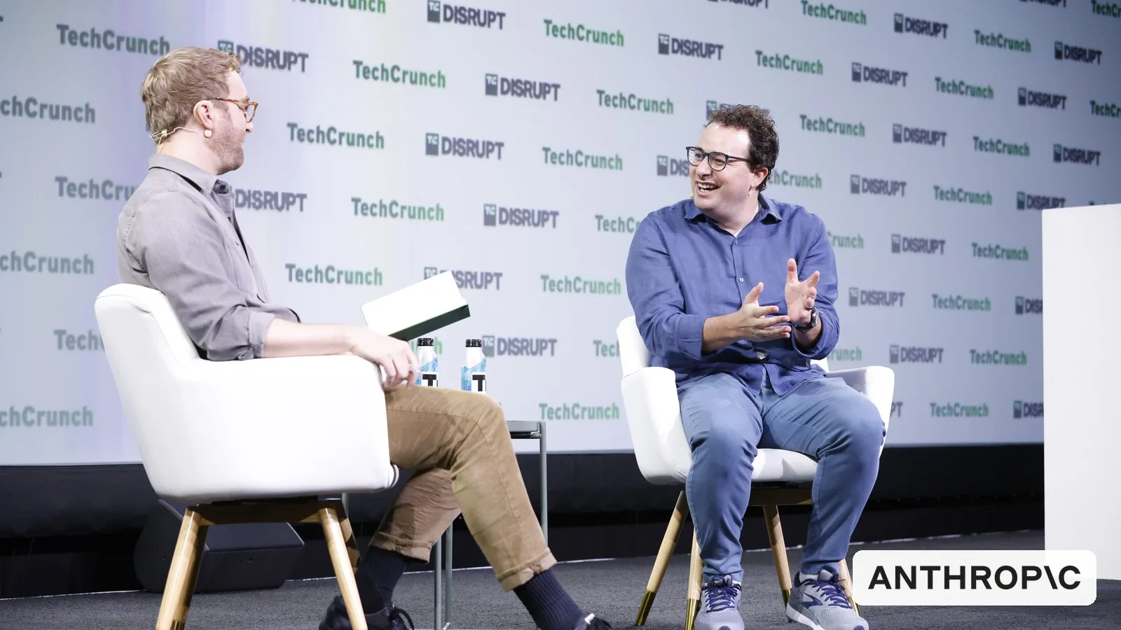 Anthropic CEO Dario Amodei (right) on stage at TechCrunch Disrupt 2023, with the Anthropic logo