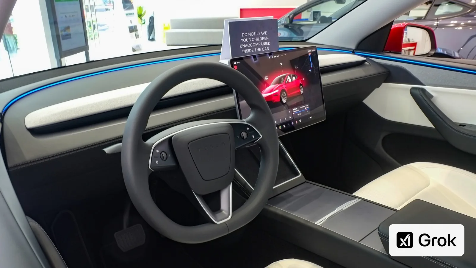 The dashboard and touchscreen of a 2025 Tesla Model Y, with the Grok logo