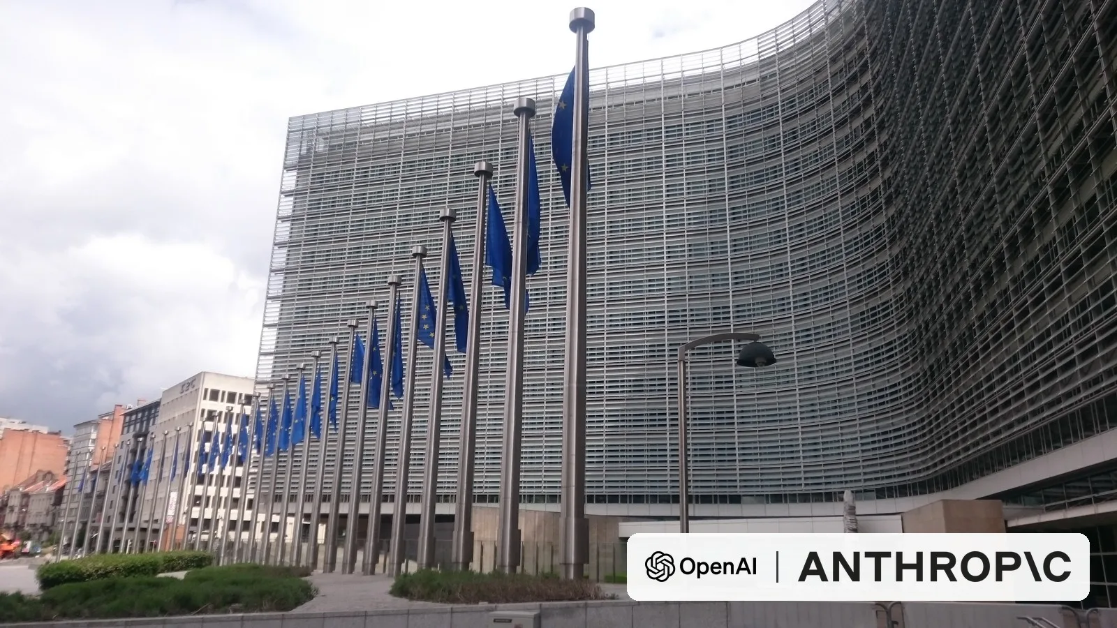 EU flags outside the Berlaymont building, the European Commission's headquarters in Brussels, with the OpenAI and Anthropic logos